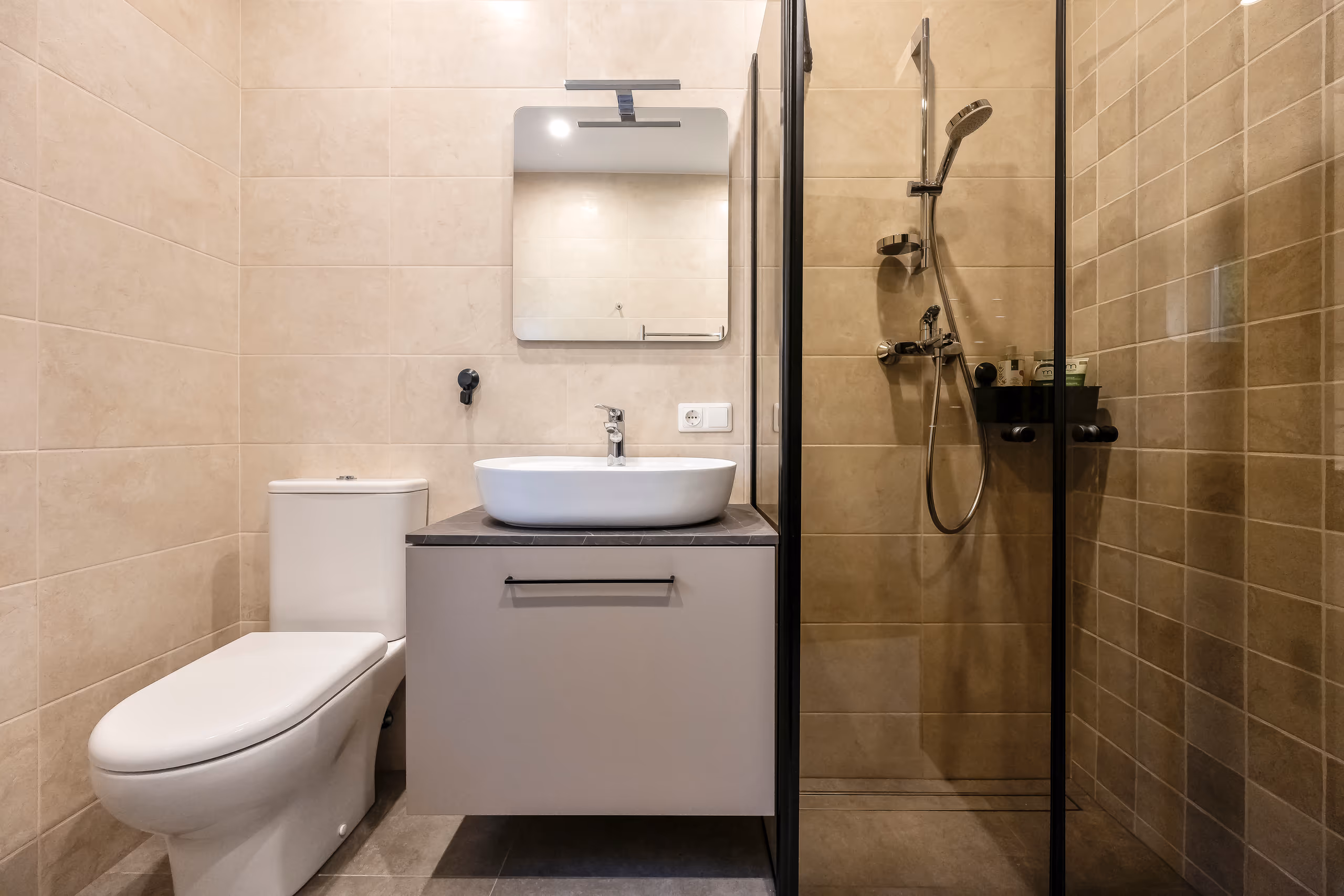 Vila Valentino bathroom with sand-coloured tiles, vessel washbasin, WC and a glass shower cabin
